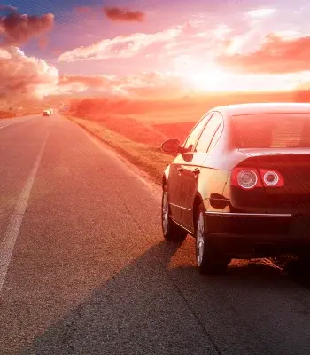 A car on a road with the sunset.