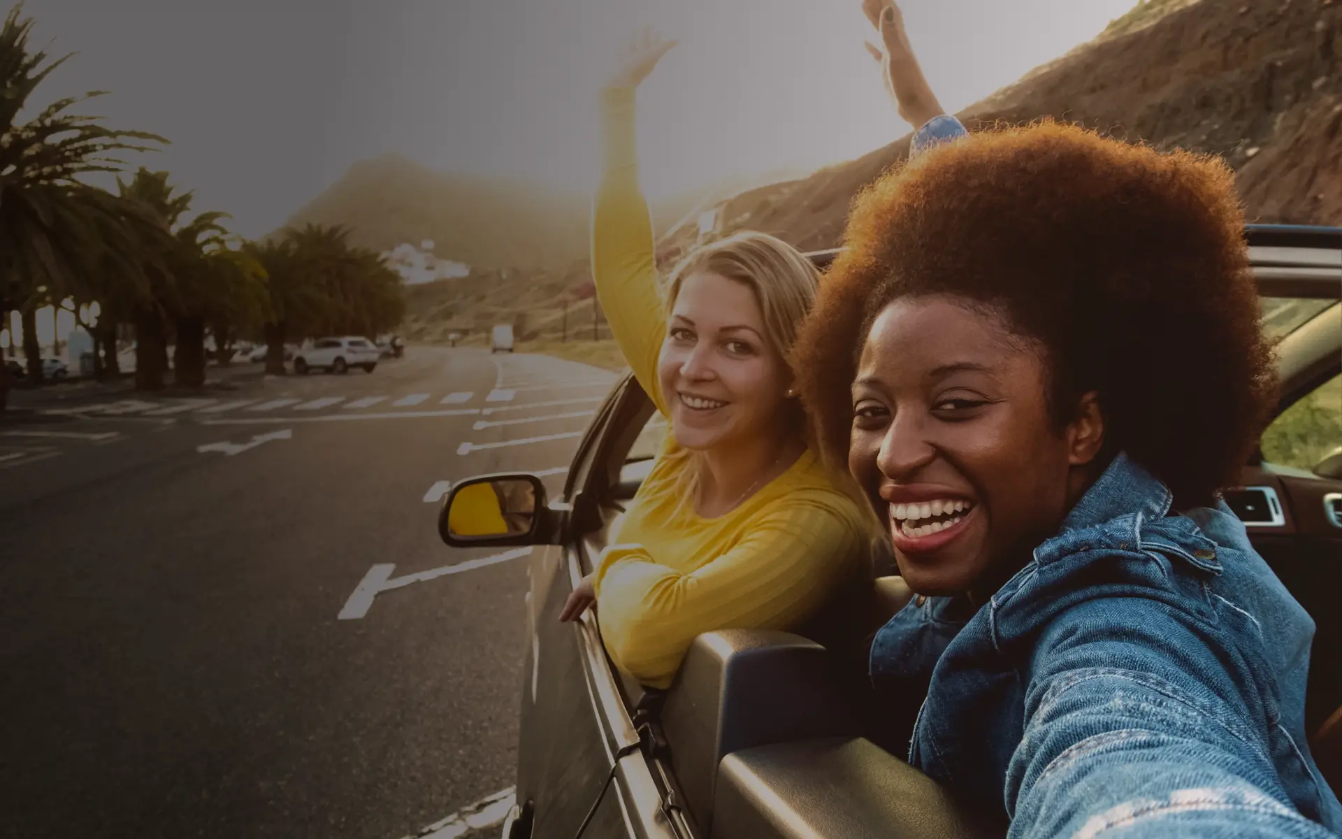 Girls having fun driving in a trendy convertible car.